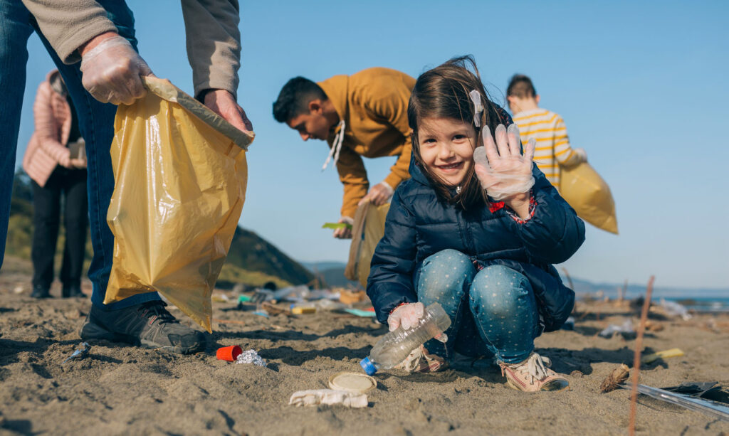Little girl picking up beach litter as a part of the Surfers against Sewage Charity, one of many great Cornish charities.