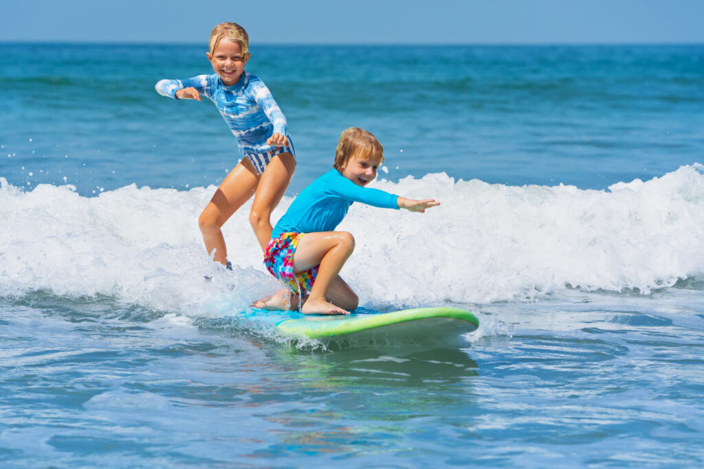 Boy and Girl riding a surfboard in Cornwall, part of the Wave Project, a great Cornish Charity.