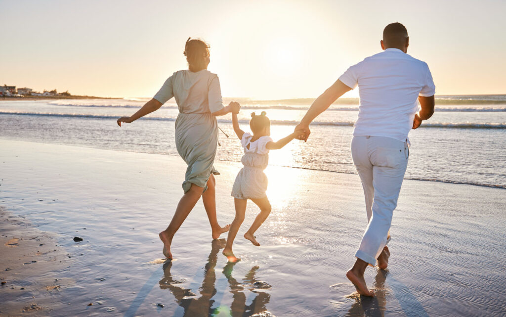 Family running across a golden beach in Cornwall.