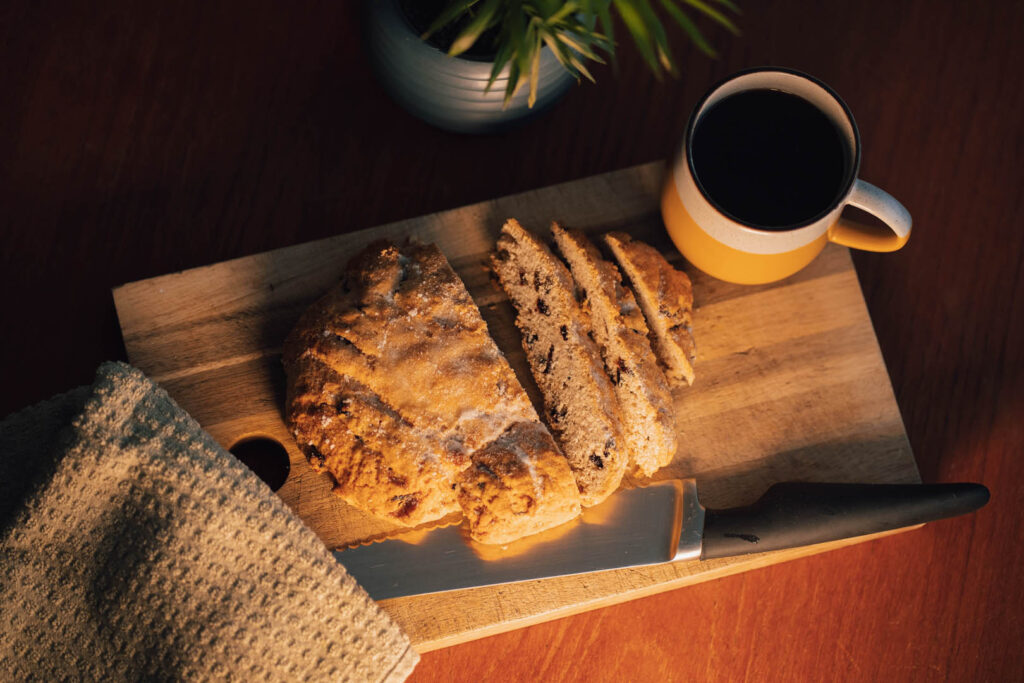 A cutting board featuring a Hevva cake and a knife, highlighting a recipe for Cornish Hevva Cake for Mother's Day.