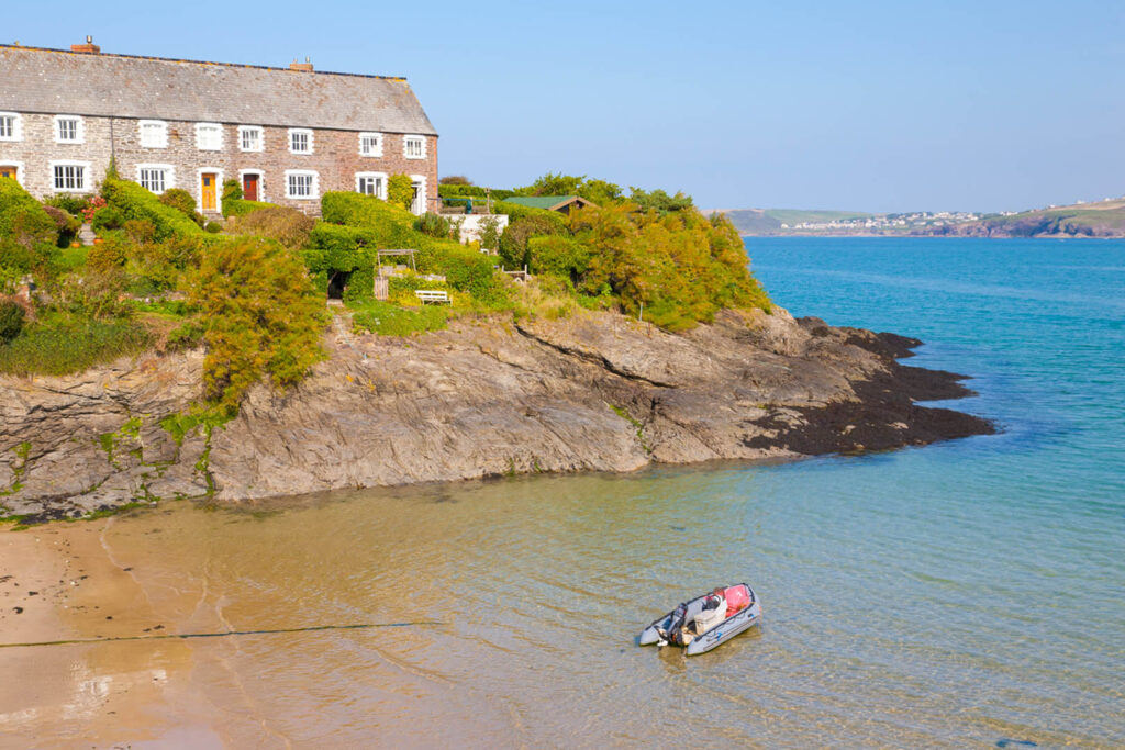 A serene view of Hawkers Cove, a tranquil body of water near Padstow, surrounded by lush greenery and sandy shores, a great local place and secret amongst locals.