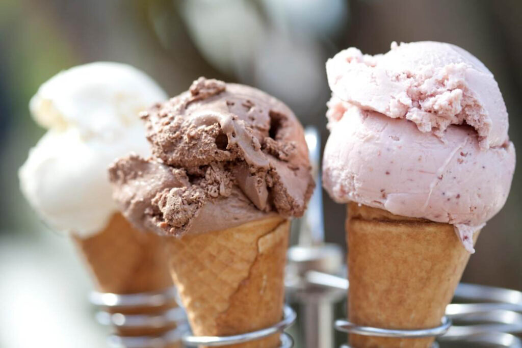 Three colourful ice cream cones displayed in a metal holder, featuring local Roskilly's Ice Cream from Cornwall.