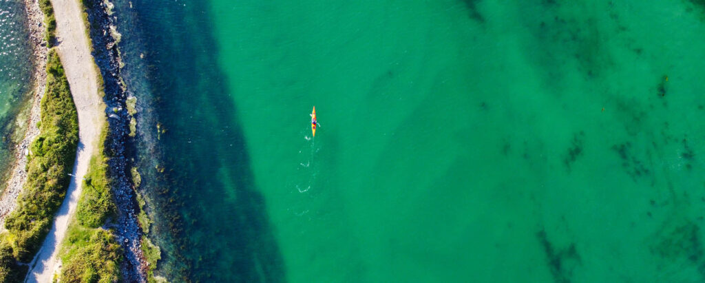 Aerial view of a canoe gliding through the tranquil waters of Hayle Estuary, showcasing the natural beauty of the area, and it's vital part to history of Hayle.