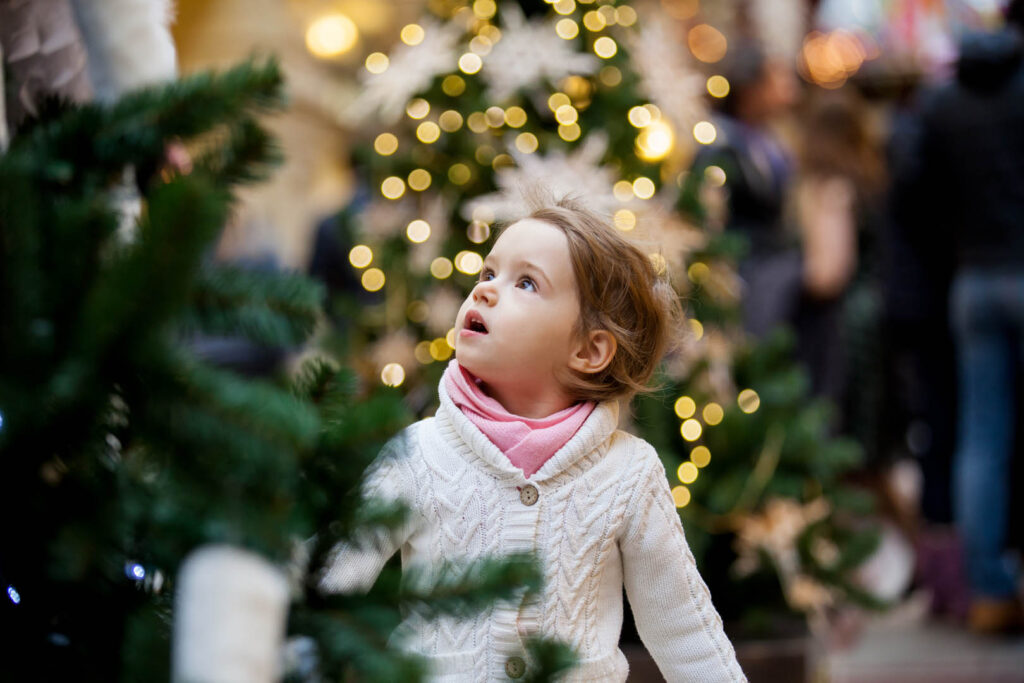 A little girl gazes up in wonder at a beautifully decorated Christmas tree in Cornwall.
