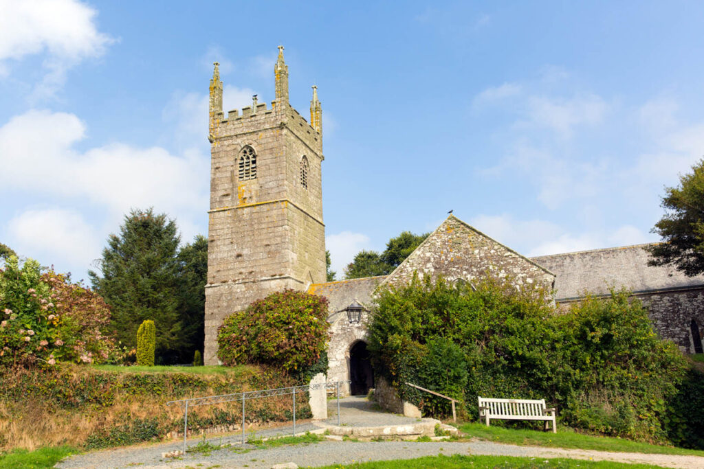 A quaint church with a steeple and a bench in front, set in St Mawgan, Newquay, a great thing to do off the beaten track.
