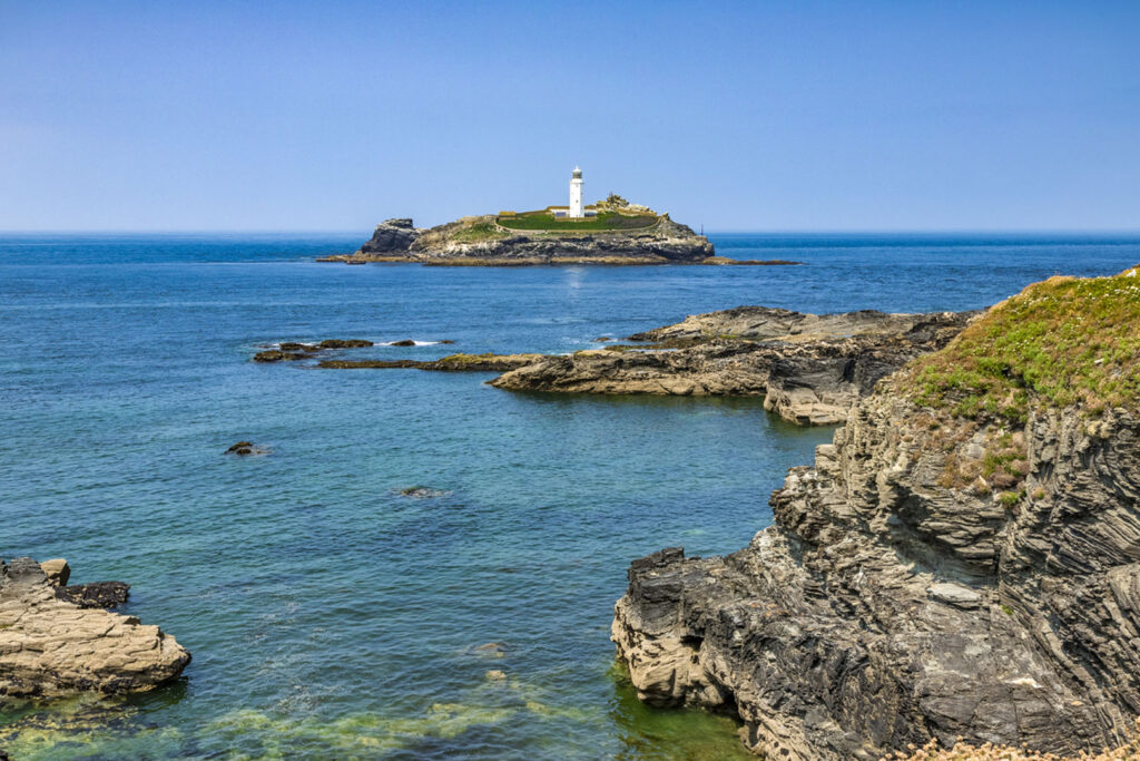 Godrevy Lighthouse on a rocky island, encircled by water, inspired Virginia Woolf's novel "To The Lighthouse.", an author inspired by Cornwall.