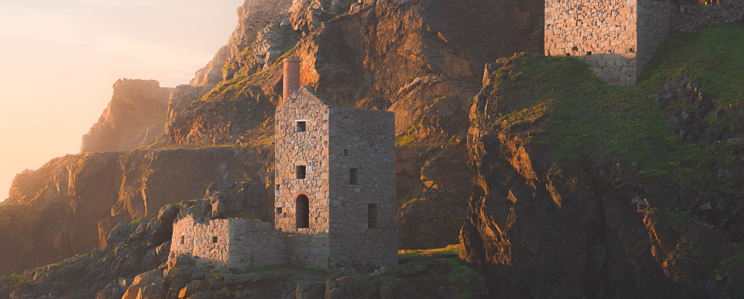 A cliffside stone building of Botallack Mine, offering stunning views of the sea and surrounding landscape in St Just, a great place to visit from a St Just and Pendeen holiday Cottage.