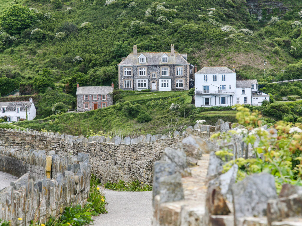 A stone wall and path lead to the iconic Doc Martin House, nestled on a hillside in Port Isaac. a great thing to see and do in Port Isaac.