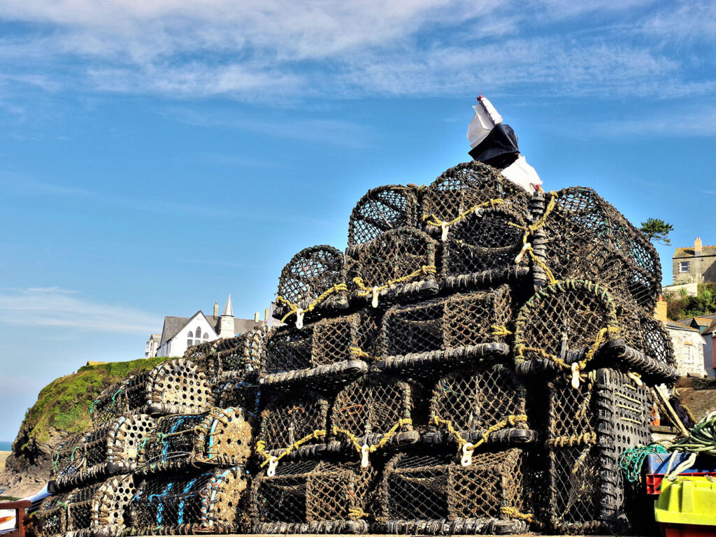 A large stack of colorful lobster traps piled together in Port Isaac, showcasing the local fishing industry, a significant part of Port Isaac's heritage.