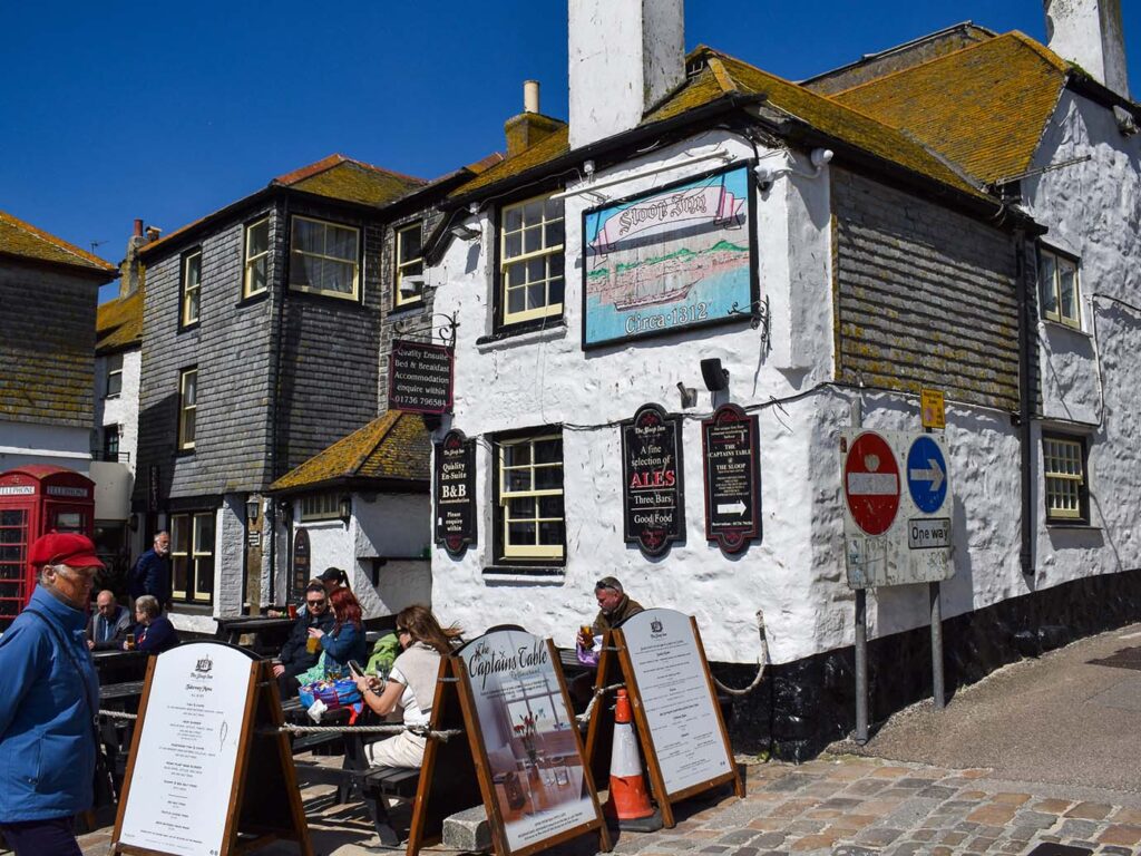 The Sloop St Ives, a white structure topped with a black roof, inviting visitors to enjoy its food and drink offerings.