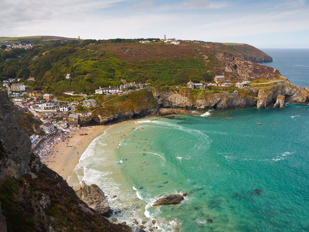 Scenic view of St Agnes Beach with the town in the background, showcasing coastal beauty and vibrant community life, a great part of St Agnes arts and heritage.