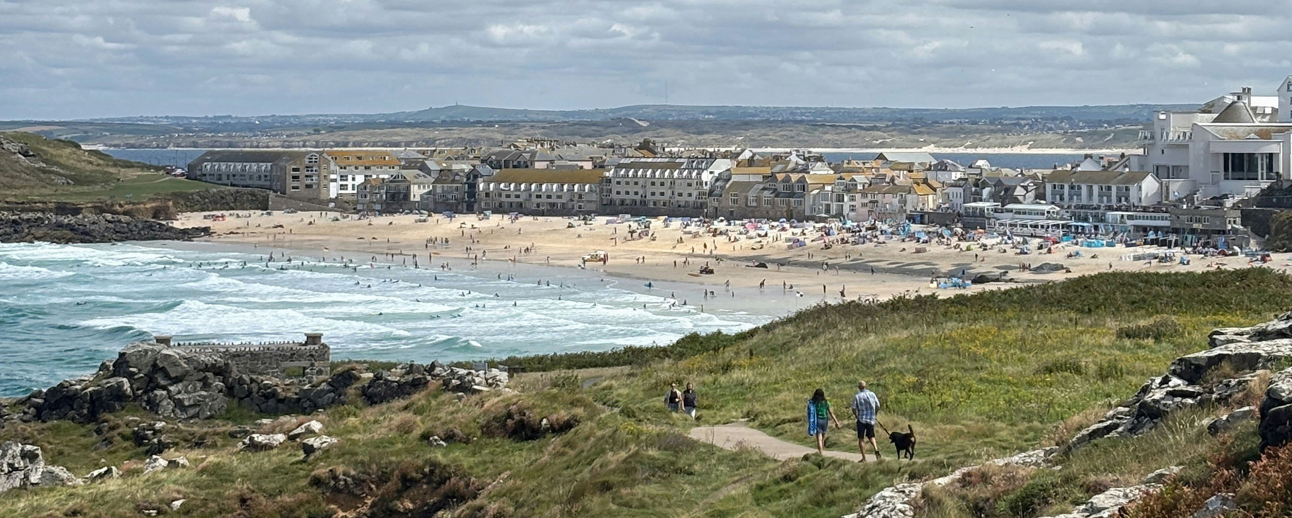 A picturesque scene of St Ives, showing Porthmeor Beach and Tate St Ives, capturing the essence of this coastal town, with its many places for food and drink.