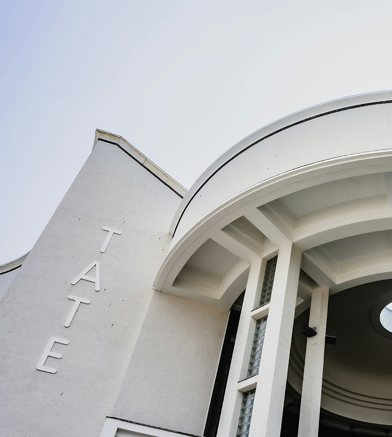 The Tate St Ives, a sleek white structure, showcases its name on a stylish sign, inviting visitors to explore art.