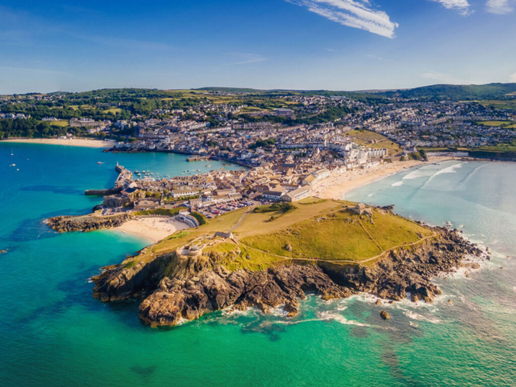 Stunning aerial shot of St Ives Bay, highlighting The Island and the picturesque town nestled along the Cornish coast, a place with lots of arts and heritage.