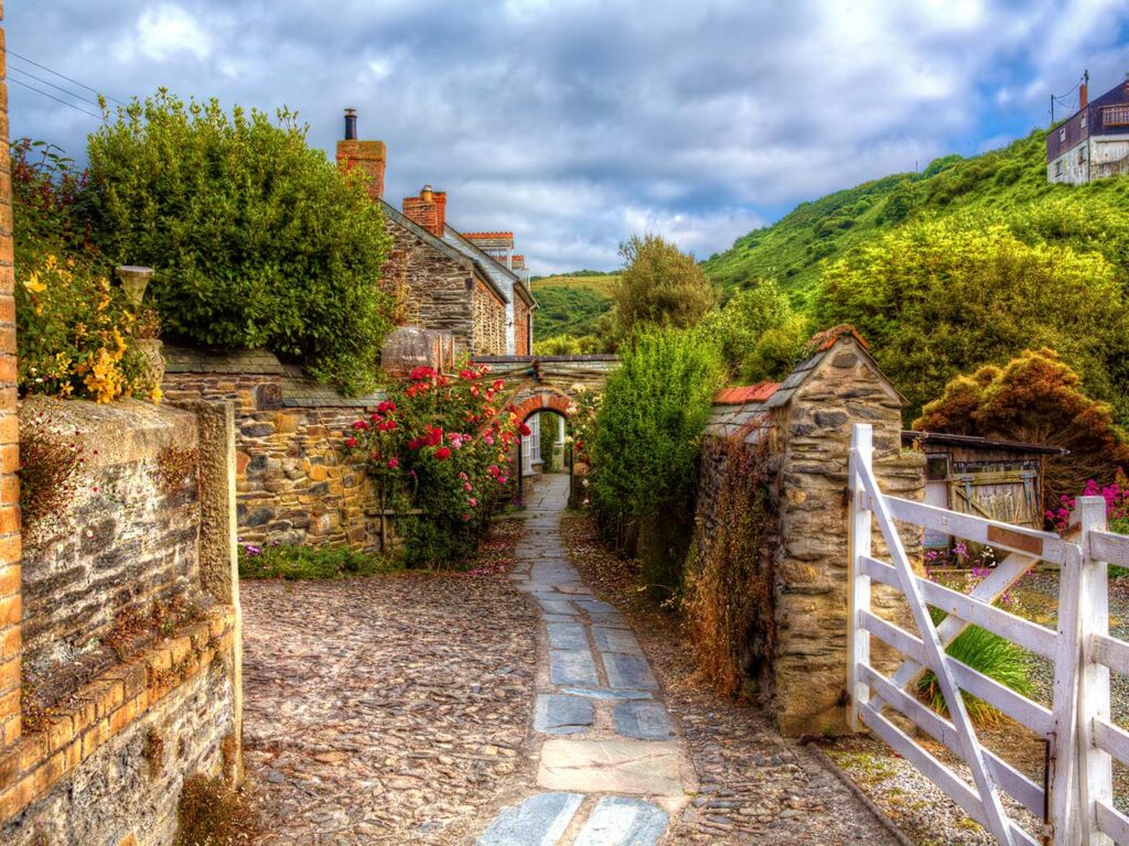 A narrow stone pathway lined with old buildings, leading through the charming village of Port Isaac, a part of Port Isaac's arts and heritage.
