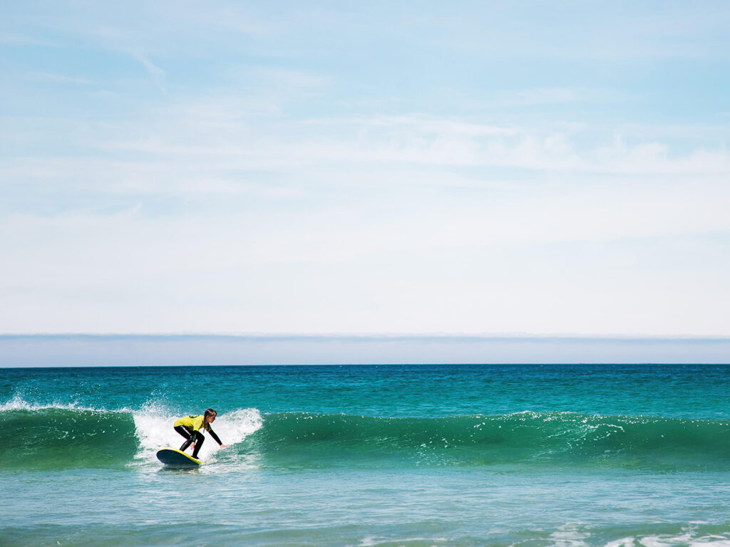 Child surfing a wave at St Ives Surf School, showcasing excitement and skill in the ocean, a great Cornish Day Out.