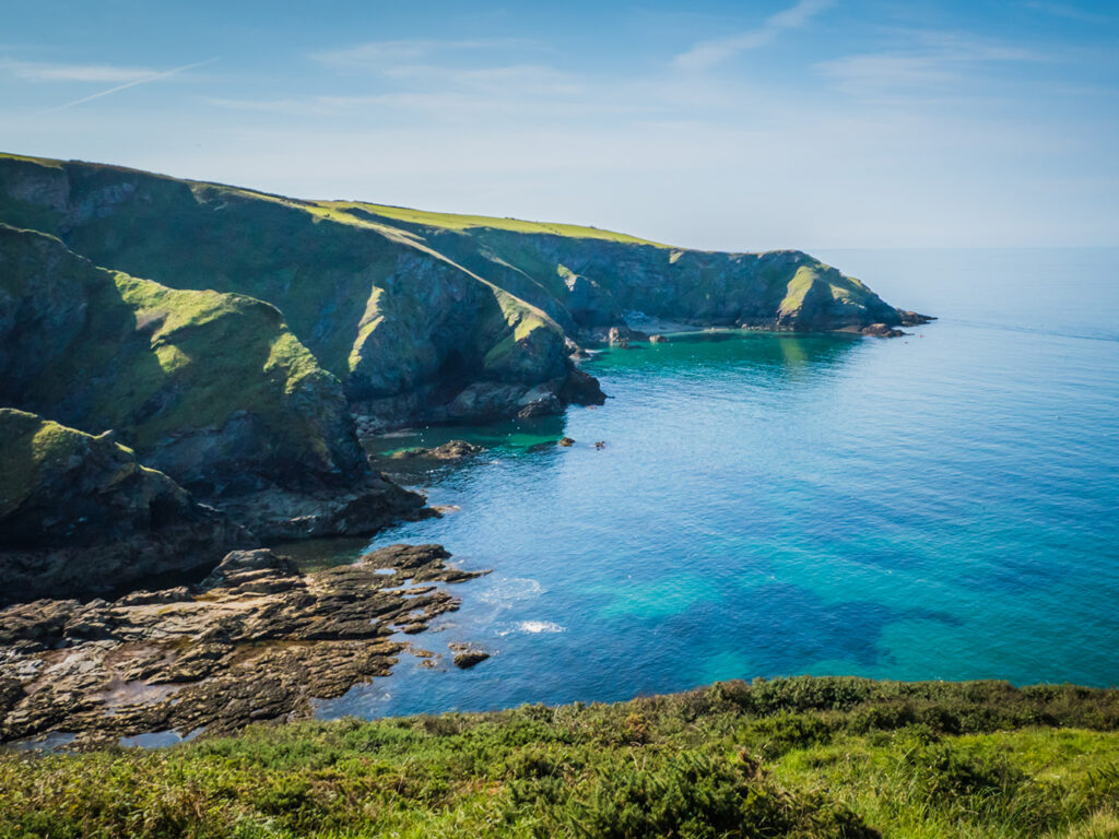 Panoramic vista of the ocean and steep cliffs from a hill near Port Isaac, highlighting the area's stunning landscape, a great thing to see and do in Port Isaac.