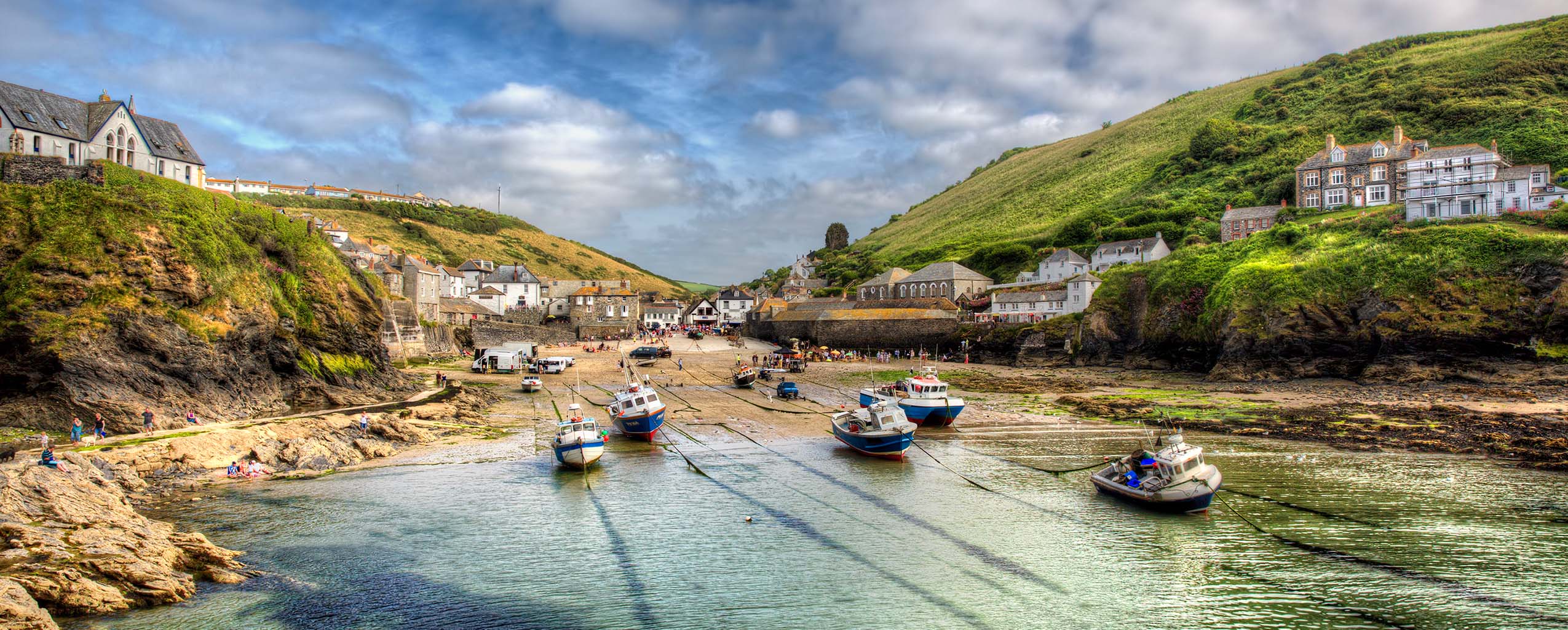 A picturesque harbour in Port Isaac with several boats docked, surrounded by charming coastal scenery, a great place for Port Isaac food and drink.