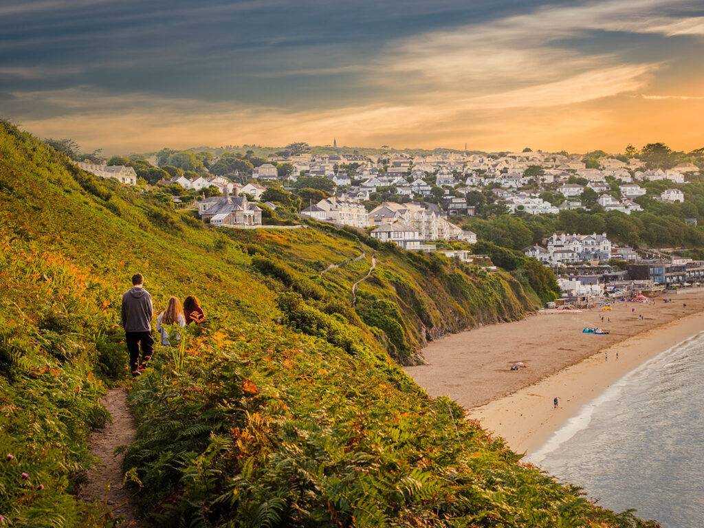A family enjoy a peaceful moment on a coastal path, overlooking the stunning beach at Carbis Bay.