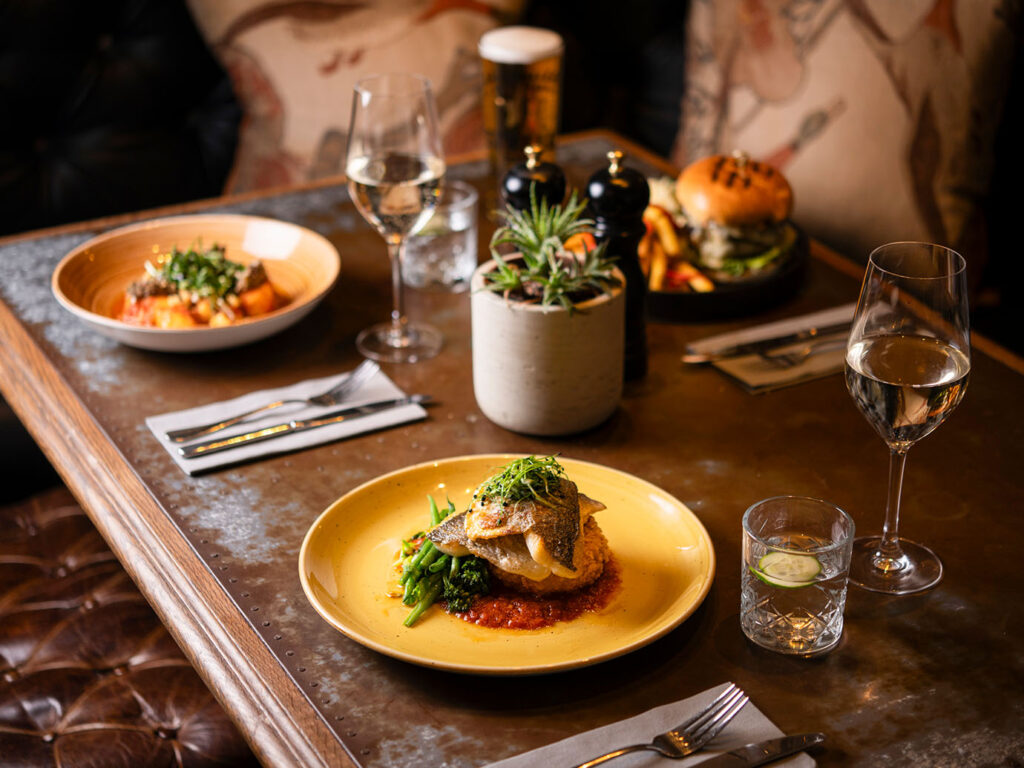 A beautifully set table at The Gannet in Carbis Bay, featuring plates of gourmet food and elegant wine glasses, an unmissable place for food and drink in Carbis Bay.
