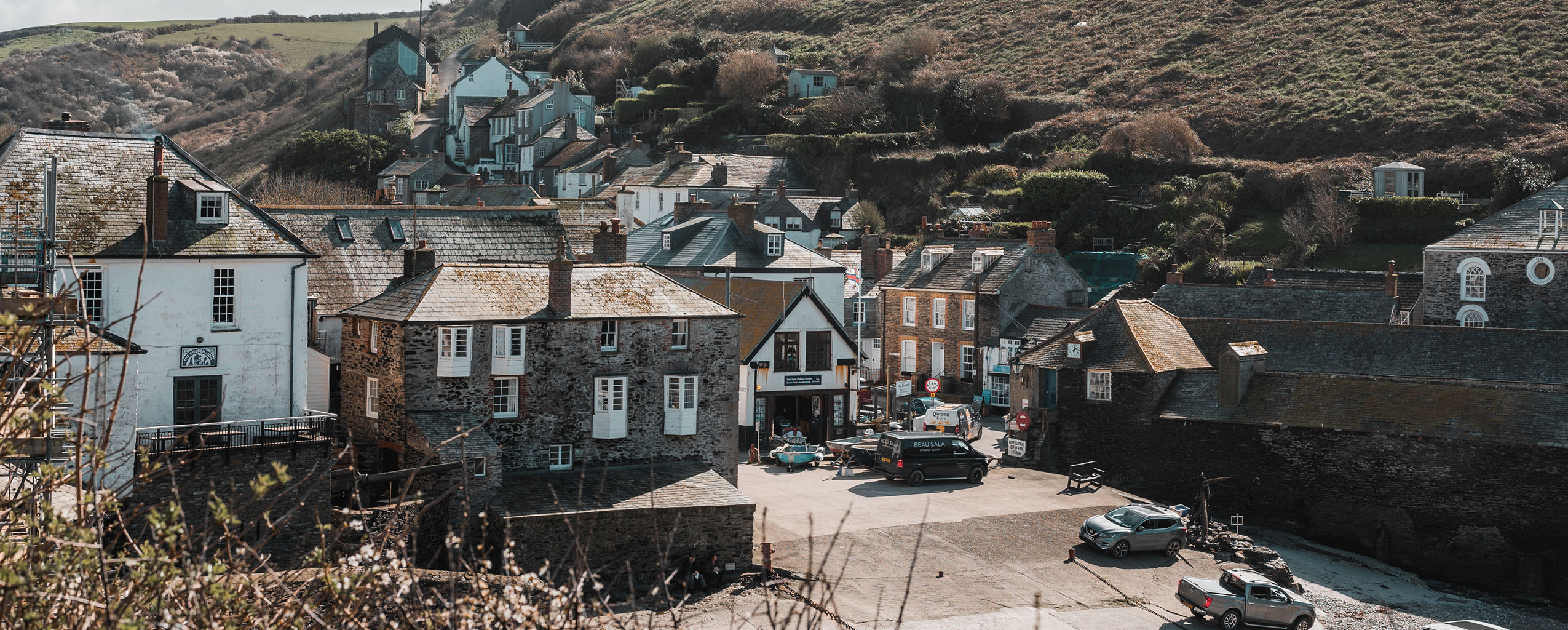 Scenic view of Port Isaac, a coastal town with charming buildings and a hill rising in the background.