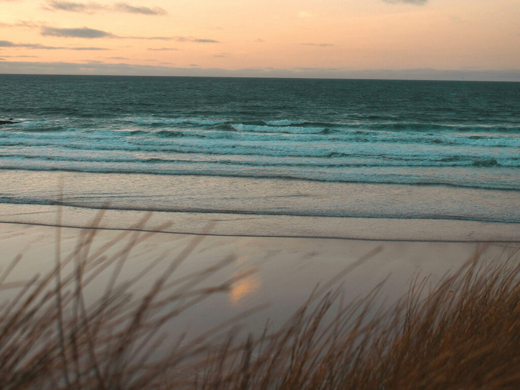 Gwithian Beach, with golden sands and a clear blue sky in the background, close to many food and drink options in Hayle.