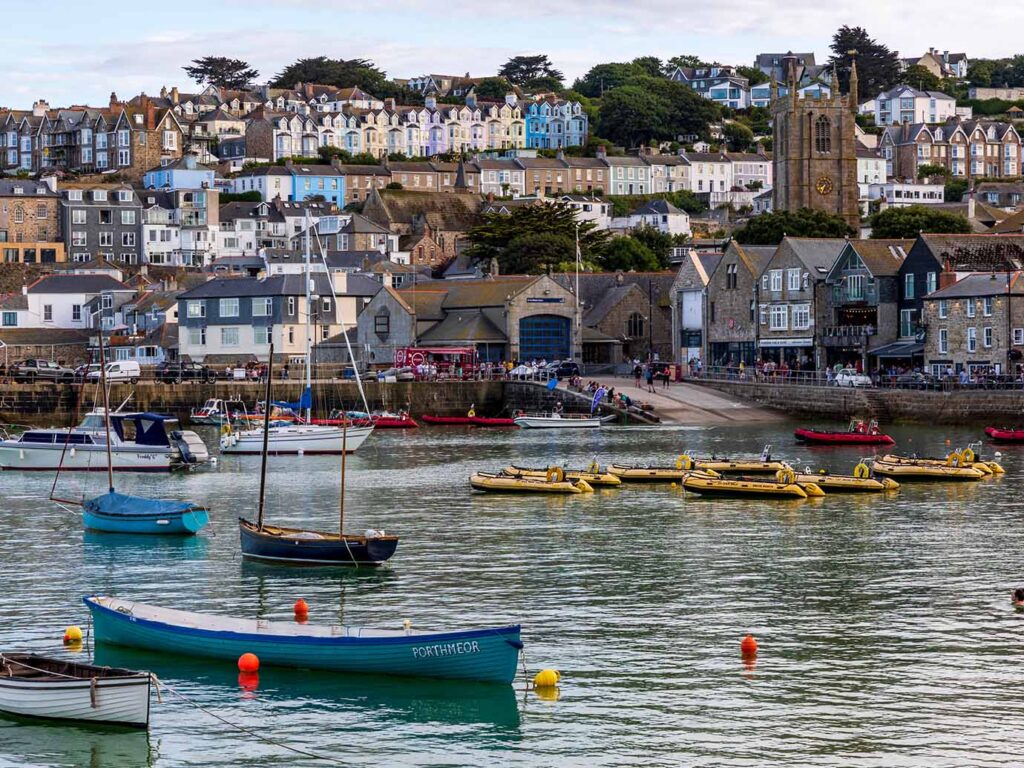 A scenic view of St Ives Harbour featuring calm waters and colorful boats bobbing gently in the bay., a place with many food and drink options.