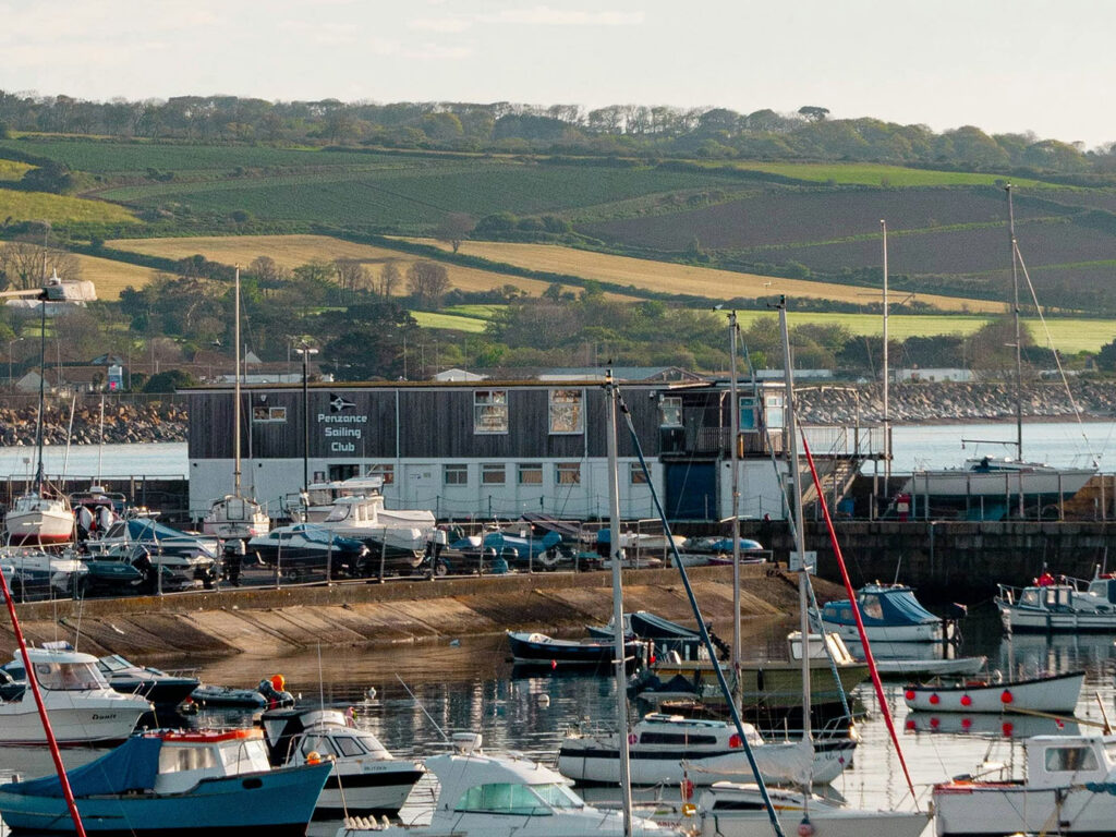 A scenic view of Penzance Harbour, showcasing a large body of water with boats and coastal scenery, a great place for food and drink in Mount's Bay.
